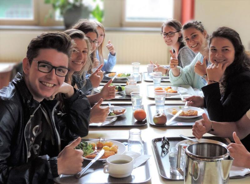 Ai campi estivi per ragazzi 16 anni i ragazzi mangiano insieme al tavolo con vassoi ricchi di cibo