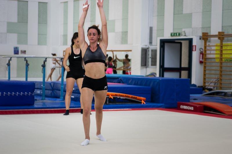 Una ragazza tiene le mani in aria prima di eseguire un'acrobazia sul tappeto del campo estivo ginnastica artistica