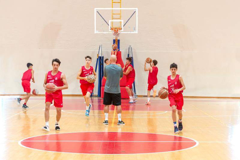 Al campo estivo basket i ragazzi stanno facendo allenamento con il coach in palestra