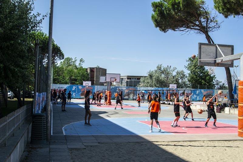 Al campo estivo basket si vedono i ragazzi che giocano su un campo in spiaggia