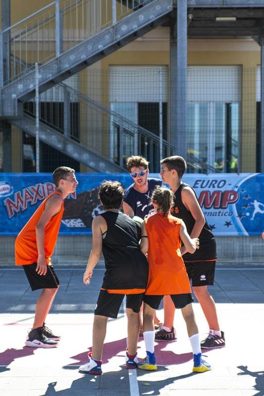 Al campo estivo basket i ragazzi di squadre opposte stanno per fare un contrasto in volo per ottenere la palla all'inizio della partita