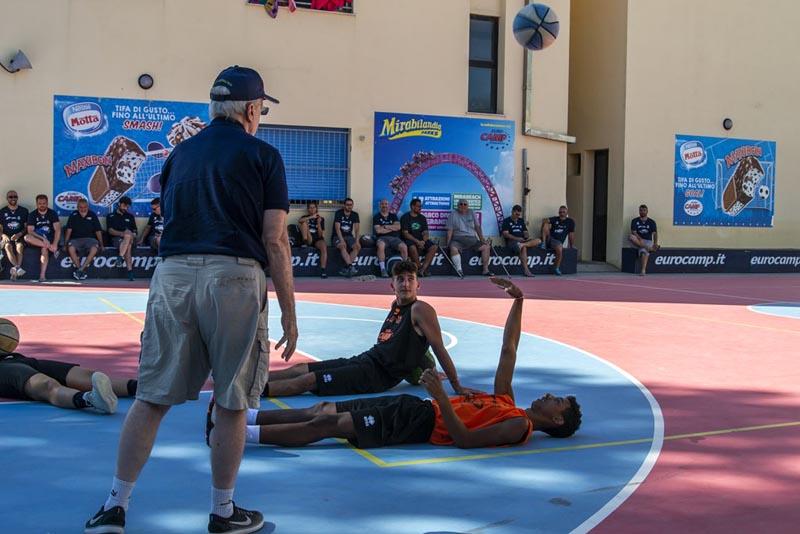 Al campo estivo basket i ragazzi sono sdraiati a terra sul campo all'aperto e uno di loro lancia in aria la palla