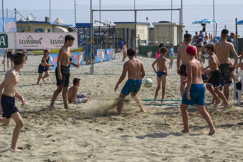 Al campo estivo calcio i ragazzi sono in spiaggia e giocano a beach soccer insieme