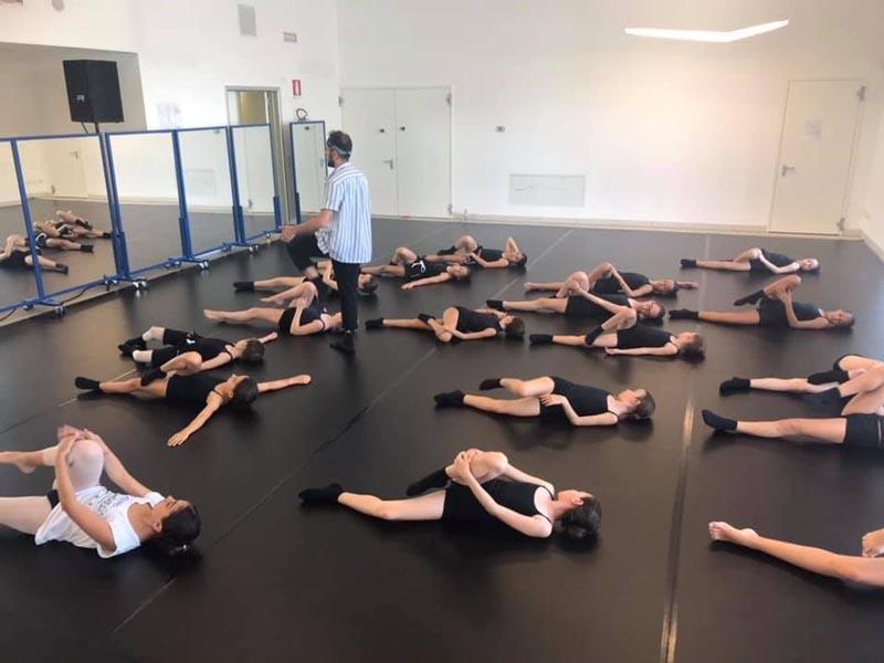Al campo estivo danza le ragazze fanno stretching a terra sotto consiglio del maestro