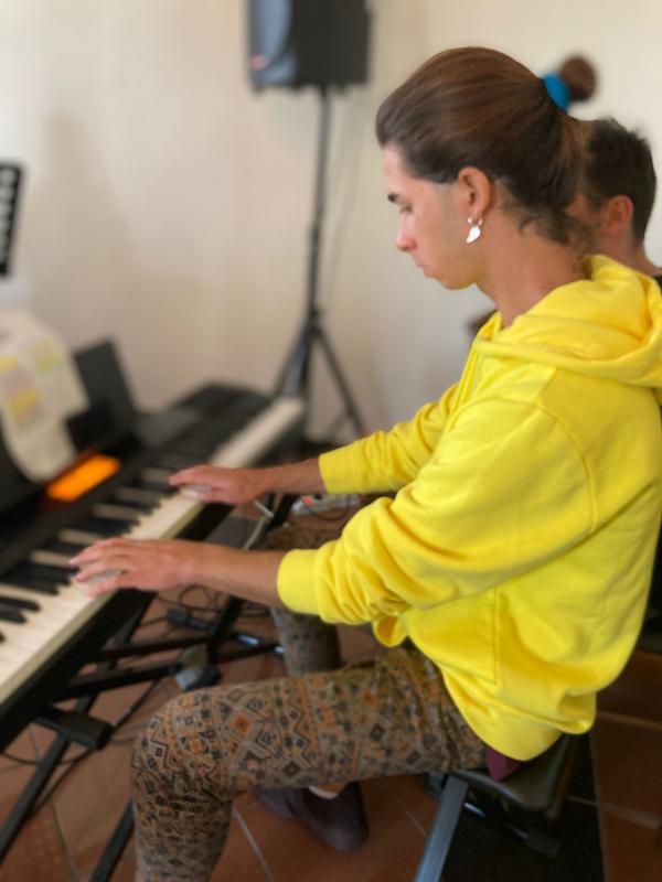 Un ragazzo con la felpa gialla suona il pianoforte al campo estivo musica