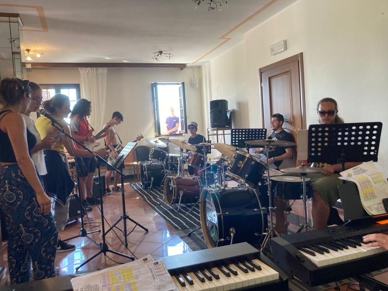 I ragazzi del campo estivo musica stanno facendo delle prove in una sala con tanti strumenti