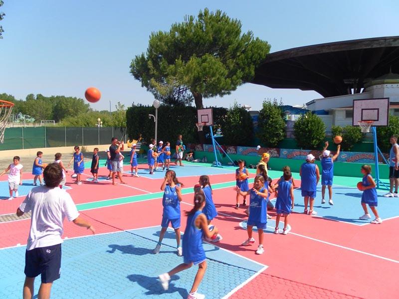 Tantissimi ragazzi si allenano a canestro su due campi colorati presso il campo estivo sport & fun