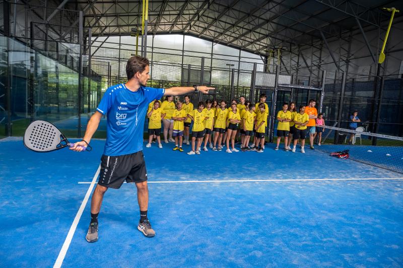 Al campo estivo sport & fun c'è un insegnante di paddle che sta mostrando ai partecipanti come svolgere l'esercizio