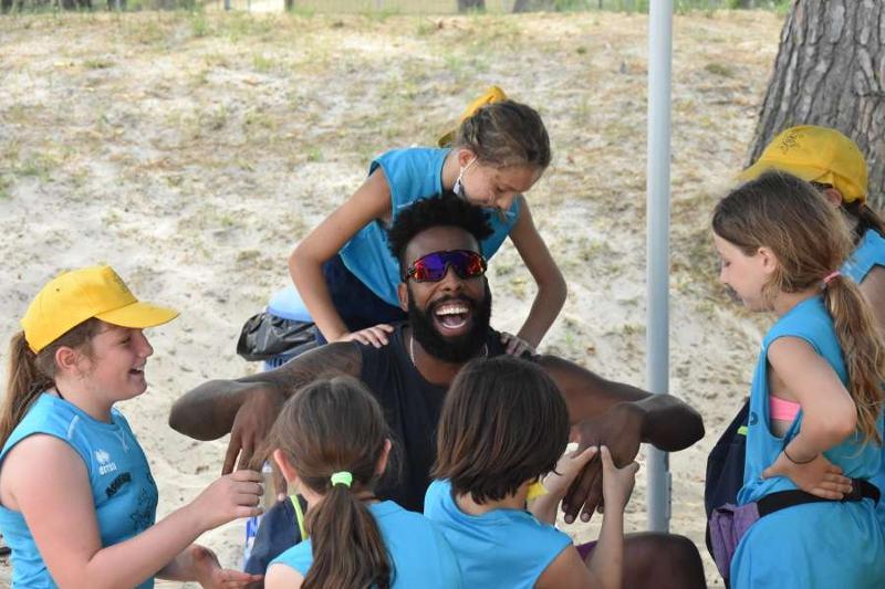 Al campo estivo pallavolo al mare le bambine ridono e giocano con l'istruttore