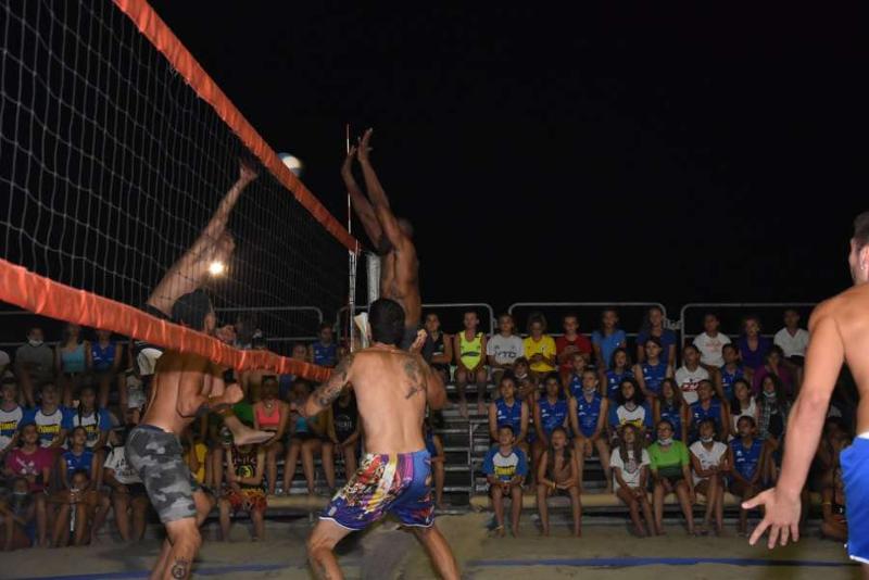 Al campo estivo pallavolo al mare i ragazzi sugli spalti guardano una partita in notturna tra professionisti