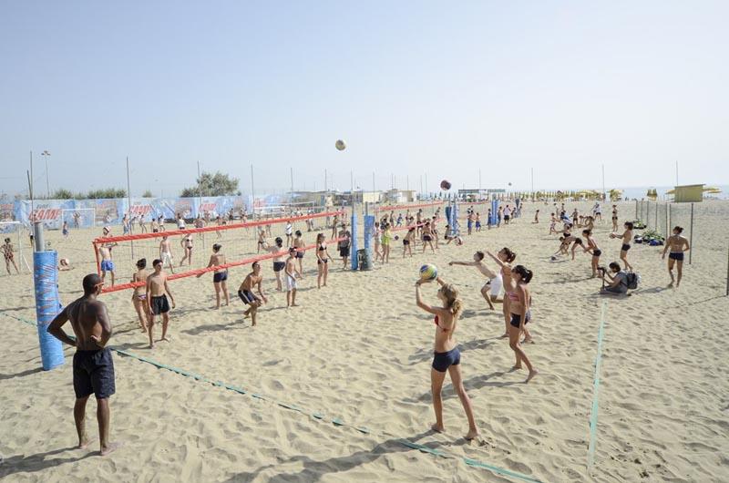 Ai campi estivi pallavolo i ragazzi giocano in spiaggia divisi su più campi