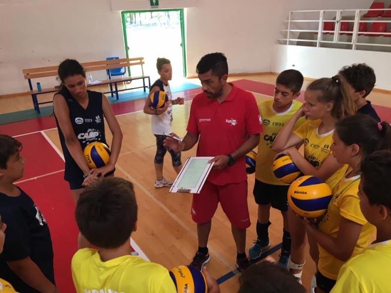 Un allenatore del campo estivo pallavolo al mare spiega ai ragazzi con una lavagnetta