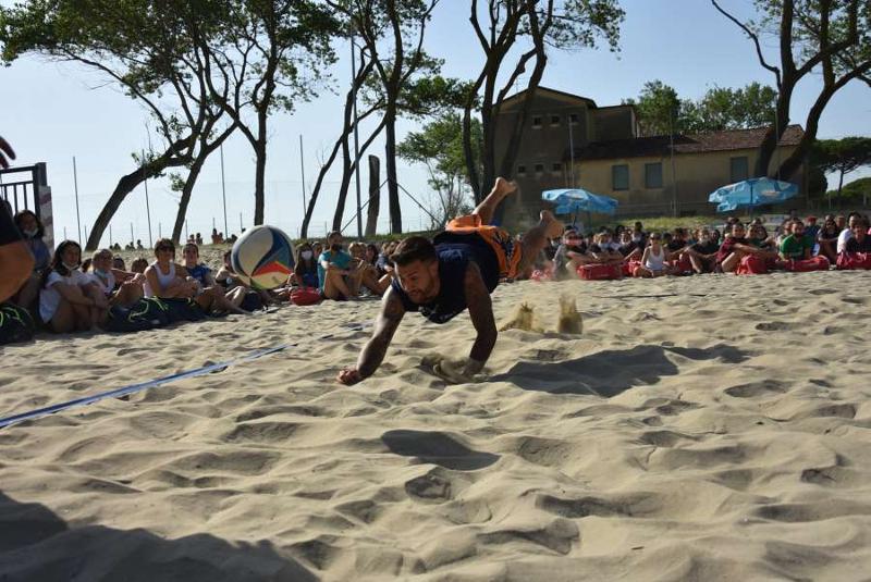 Un giocatore si tuffa sulla spiaggia al campo estivo pallavolo