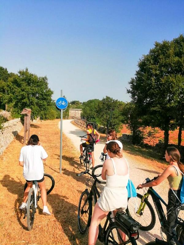 Al soggiorno linguistico italiano ad Alberobello ci sono le ragazze che stanno andando in bicicletta 