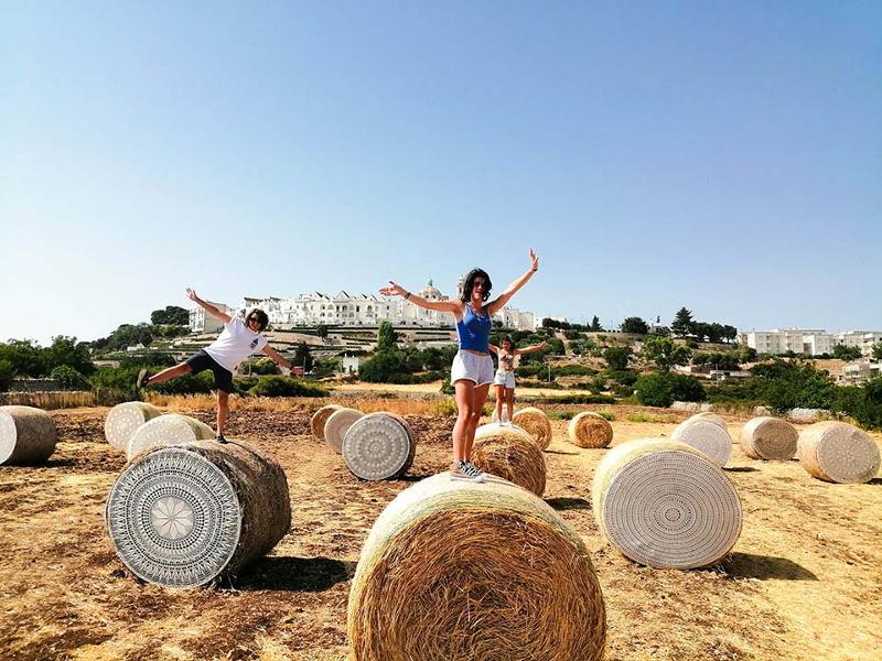 Al soggiorno linguistico italiano ad Alberobello ci sono tre ragazzi che si fanno una foto mentre sono in equilibrio su le balle di fieno 