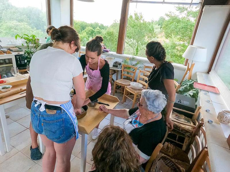 Al soggiorno linguistico italiano ad Alberobello le studentesse stanno cucinando con la nonna in cucina