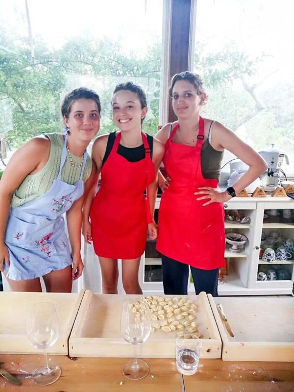 Al soggiorno linguistico italiano ad Alberobello tre ragazze si fanno una foto con il grembiule davanti alla pasta che hanno fatto