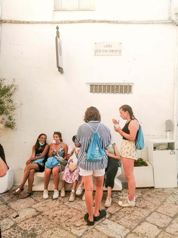 Al soggiorno linguistico italiano ad Alberobello i ragazzi sono seduti sul muretto che mangiano un gelato tutti insieme