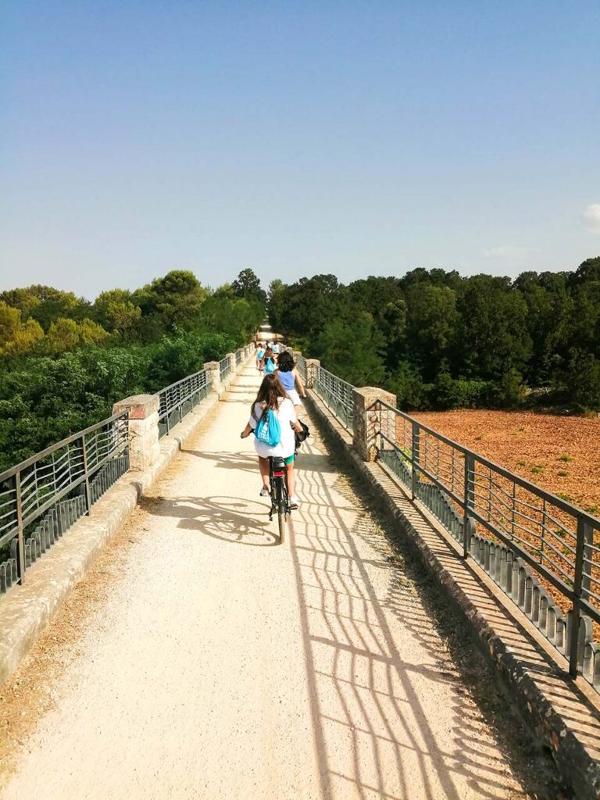 Al soggiorno linguistico italiano ad Alberobello ci sono i ragazzi su un ponte che vanno in bicicletta 