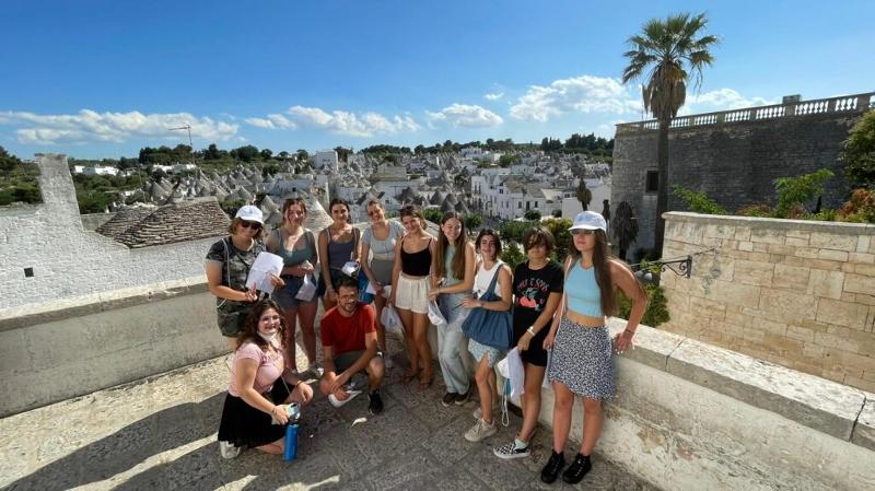 Al soggiorno linguistico italiano ad Alberobello i ragazzi fanno una foto di gruppo insieme e nello sfondo ci sono i trulli 