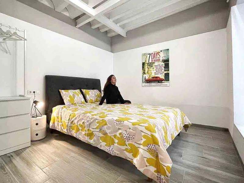 Ti sentirai a casa al soggiorno linguistico spagnolo Una ragazza siede su un letto bianco e giallo in una delle stanze del soggiorno linguistico spagnolo