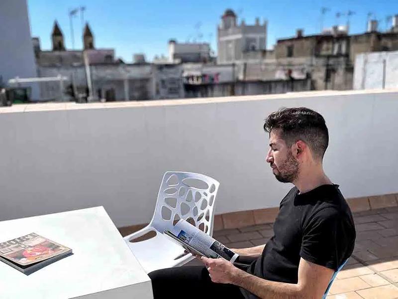 Al soggiorno linguistico spagnolo un ragazzo legge una rivista sul balcone
