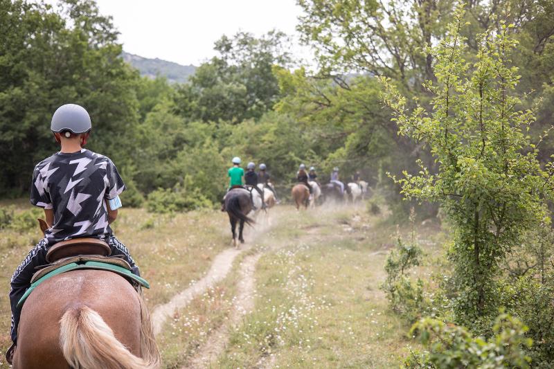 Al campo estivo Abruzzo i ragazzi fanno una passeggiata a cavallo con i caschi