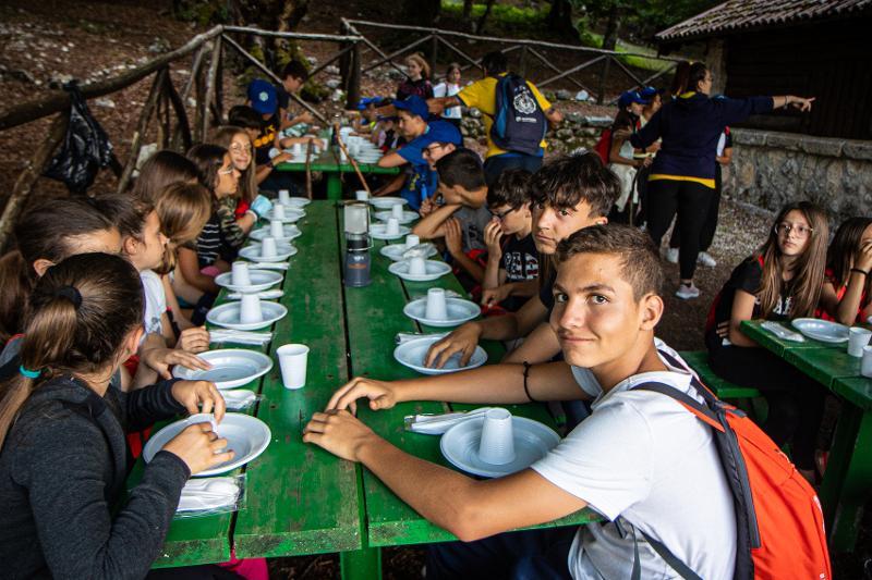 Al campo estivo Toscana i ragazzi seduti ai tavoli stanno mangiando tutti insieme