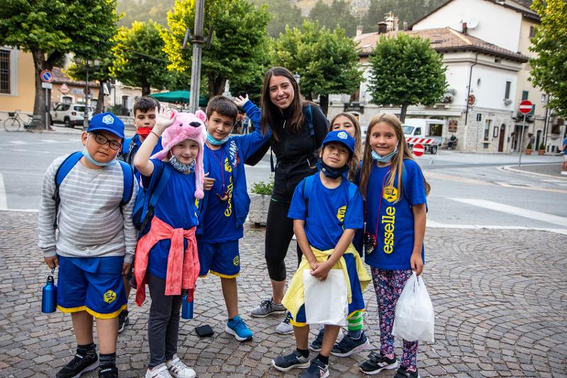 I bambini sorridono con la loro insegnante in giro per la città al campo estivo bambini