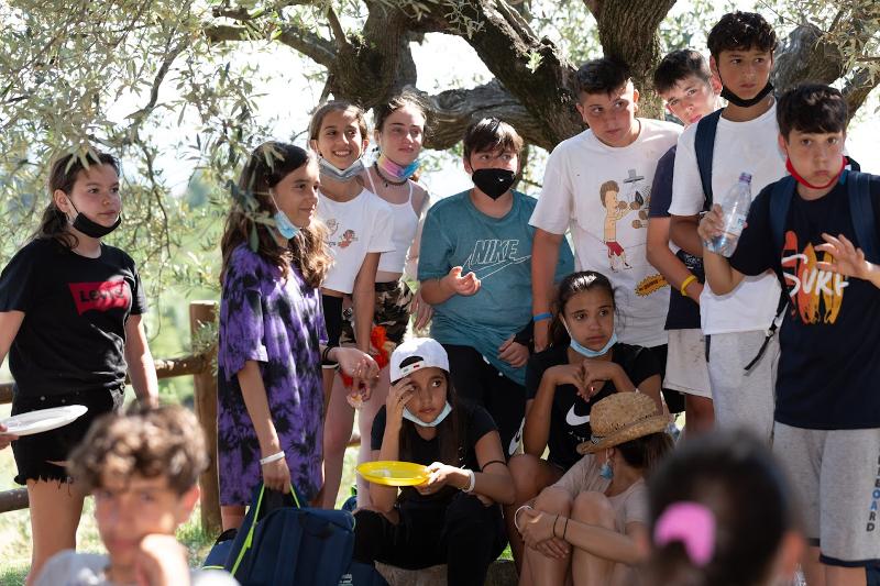 Ai campi estivi per ragazzi, i ragazzi pranzano all'aperto mentre ascoltano divertiti