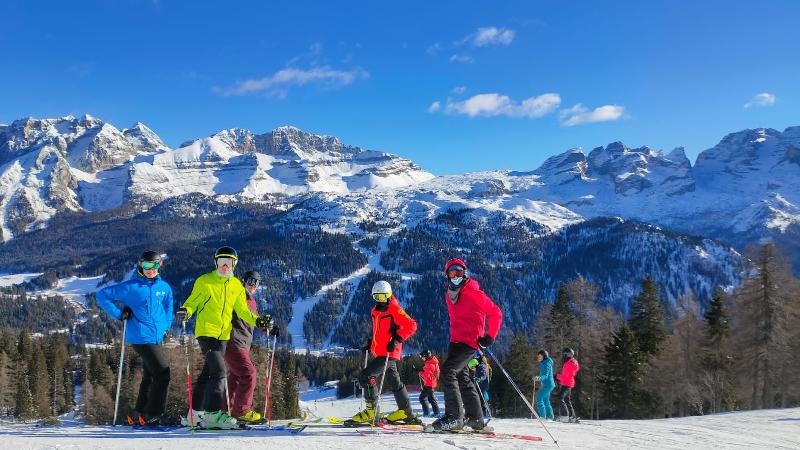 Durante il campo invernale, alcuni ragazzi vestiti da sci posano sulla neve con sfondo montano