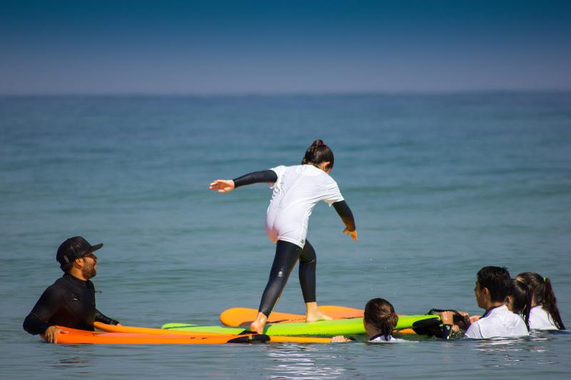 Una ragazza del campo estivo surf salta da una tavola all'altra in acqua