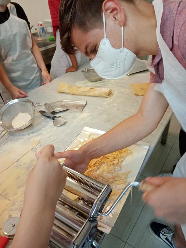 Ai viaggi organizzati Toscana un ragazzo sta facendo la pasta fresca
