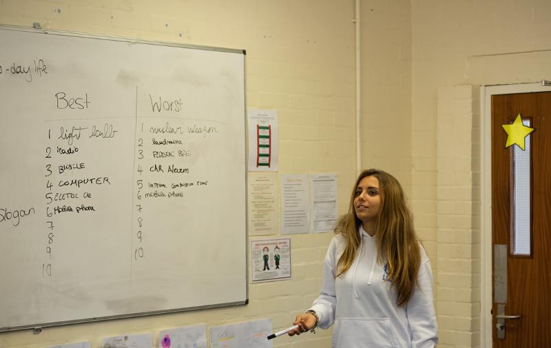 Ragazza che scrive ad una lavagna con dei pennarelli mentre cerca di spiegare qualcosa, probabilmente stavano facendo un giorno al soggiorno in lingua inglese nel cuore della Scozia