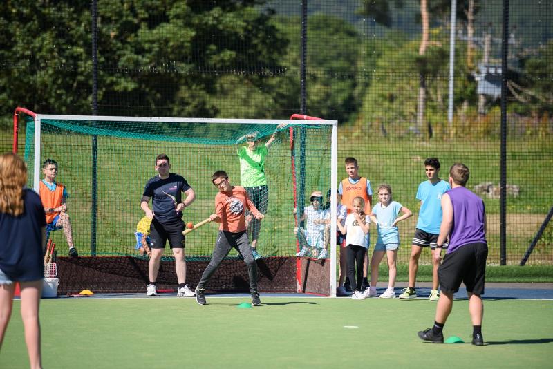 Gruppo di ragazzi che gioca a cricket in un campo all'aperto al soggiorno in lingua inglese nel cuore della Scozia