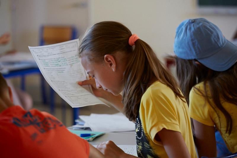 Al soggiorno linguistico francese una bambina si sta concentrando per fare i suoi compiti 