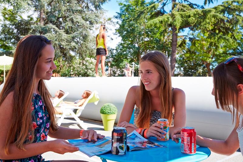 Al soggiorno linguistico francese le ragazze stanno parlando tra di loro al bar esterno della scuola sorseggiando una bevanda 