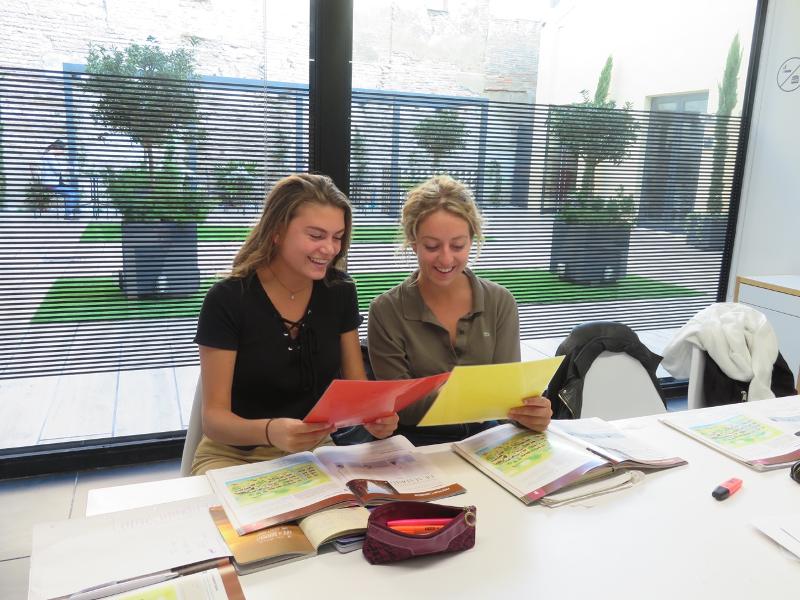 Due ragazze partecipanti al soggiorno linguistico spagnolo eseguono attività didattiche in classe