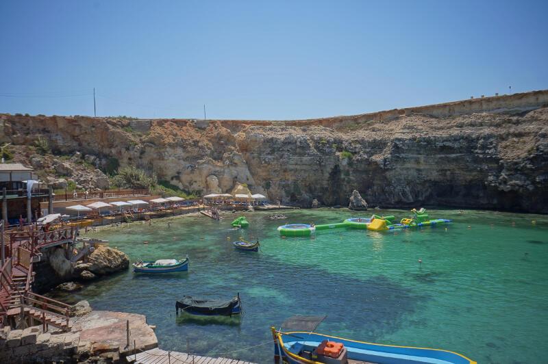 Ai viaggi organizzati Salento ci sono piccoli pescherecci e gonfiabili galleggianti davanti ad una spiaggia che si affaccia sul limpido mar Ionio