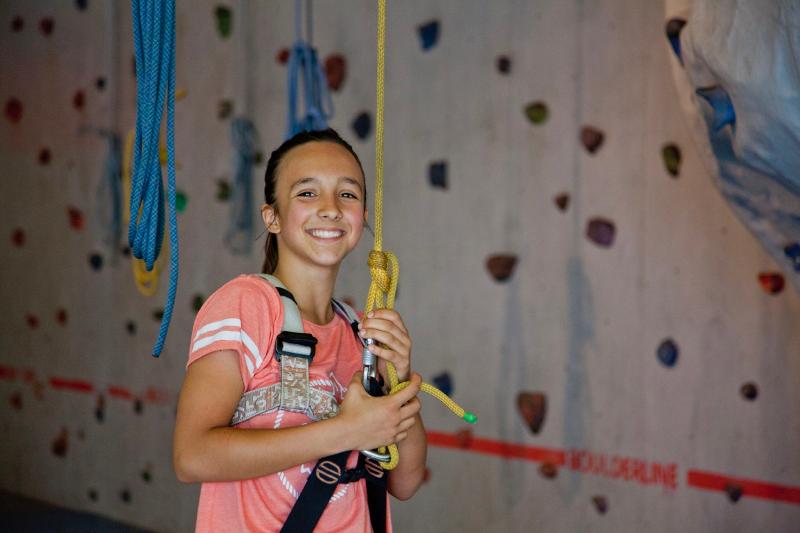 Una ragazza del soggiorno linguistico tedesco è legata a una corda da arrampicata e sorride