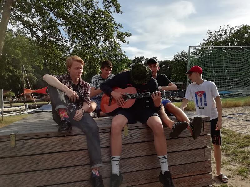 Un gruppo di ragazzi del soggiorno linguistico tedesco ascolta un altro partecipante suonare la chitarra