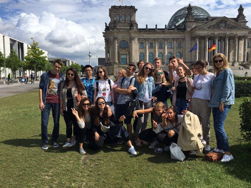 Gruppo di ragazzi e ragazze posa per una foto di gruppo davanti al Reichtag e alla torre della televisione a Berlino