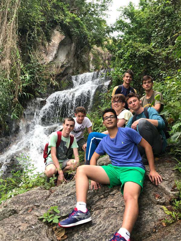 ragazzi seduti accanto a una cascata durante un campo in Asia