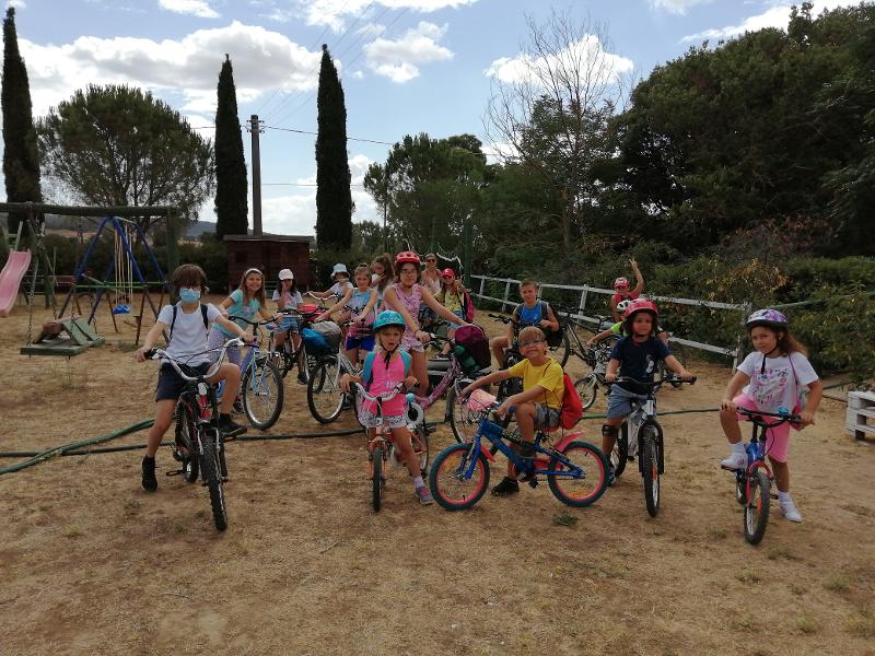 Ai campi estivi in fattoria c'è un gruppo di bambini in bicicletta