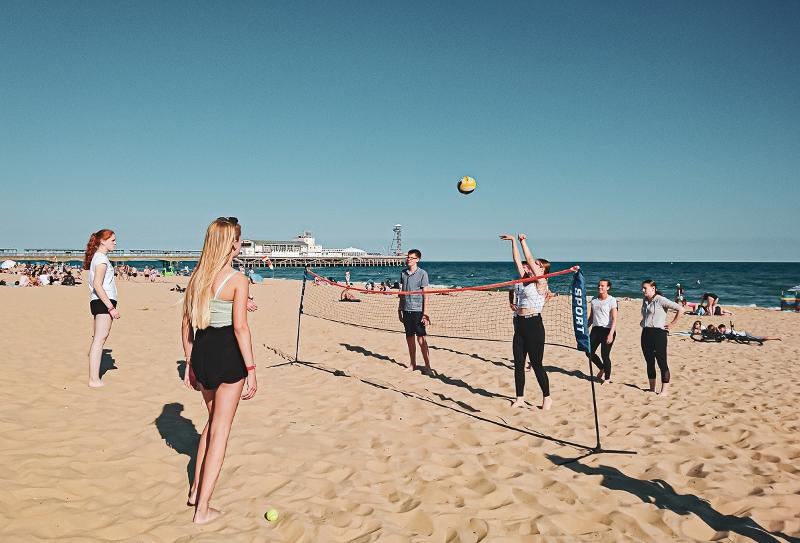 Al soggiorno linguistico inglese estivo a Bournemouth ci sono dei ragazzi in spiaggia in riva al mare che stanno giocando a pallavolo 
