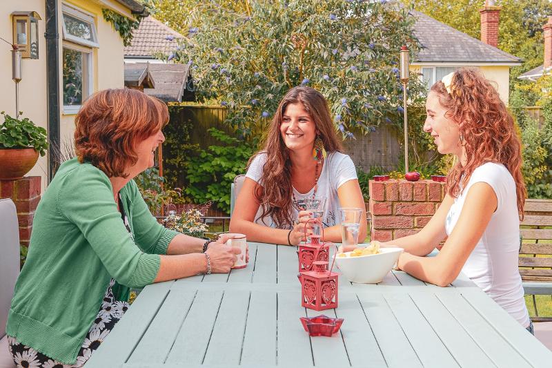 Al soggiorno linguistico inglese estivo a Bournemouth ci sono due ragazze che stanno parlando con una donna in giardino  