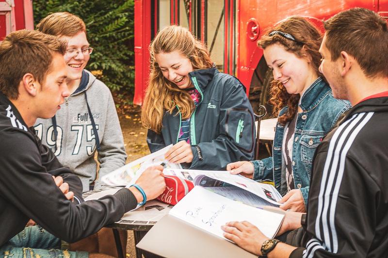 Al soggiorno linguistico inglese estivo a Bournemouth ci sono cinque ragazzi che stanno leggendo i libri di scuola insieme all'aperto 