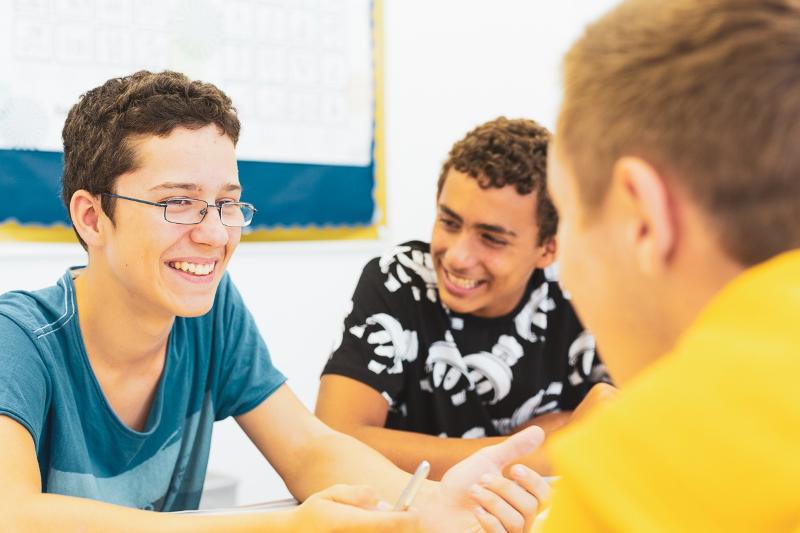 Al soggiorno linguistico inglese estivo a Bournemouth ci sono tre ragazzi che stanno parlando tra di loro e sorridono 