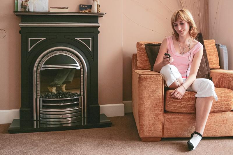 Al soggiorno linguistico inglese estivo a Bournemouth c'è una ragazza che si sta rilassando ascoltando la musica sul divano