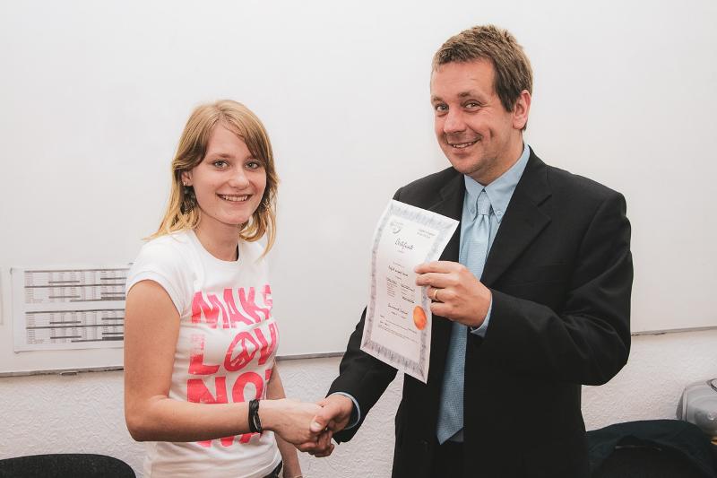 Al soggiorno linguistico inglese estivo a Bournemouth c'è una ragazza che sorride e stringe la mano al professore che le da l'attestato del corso 